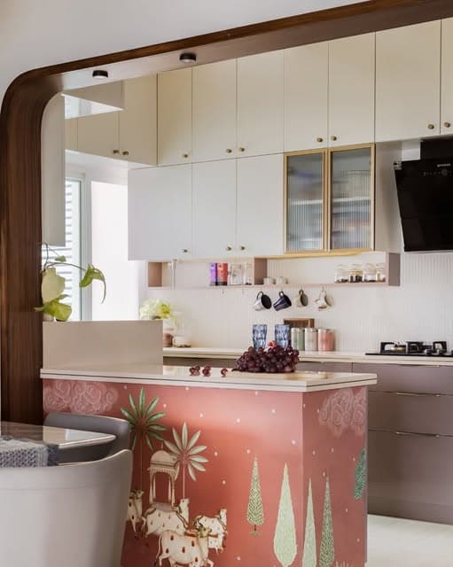 A pink illustrated counter brings a playful focal point to a cream kitchen, framed by a gently curved opening.