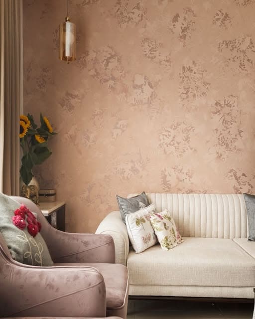 A softly textured wall, curved seating and floral cushions create a warm, layered sitting corner.