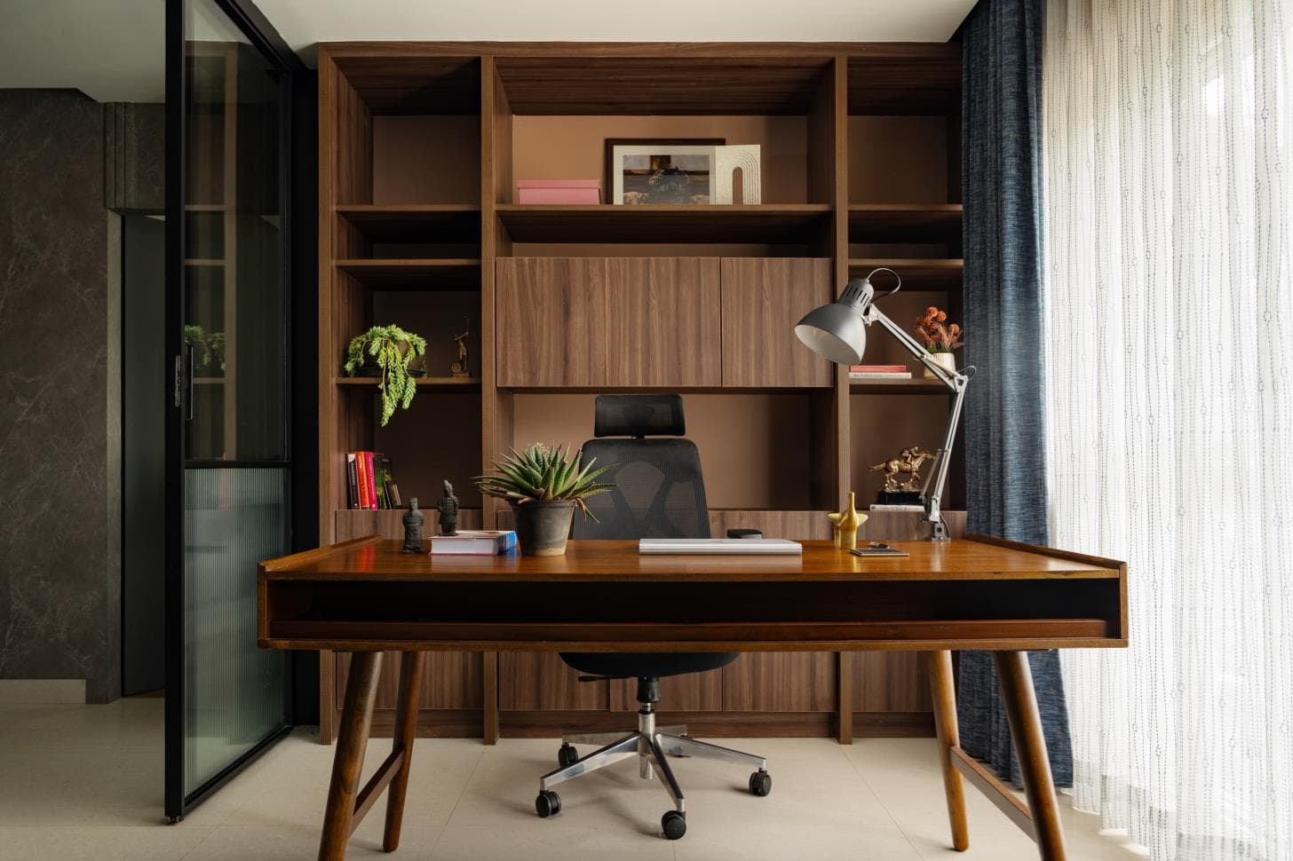 Built-in study desk in warm wood tones with open shelving and a task chair