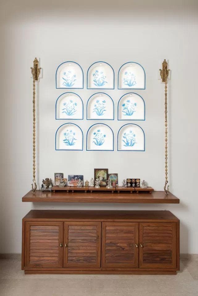 Pooja corner with a carved wooden backdrop and warm ambient lighting
